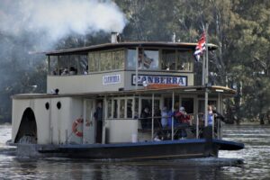 A paddle steamer boat on the Murray river with steam coming out of the boat