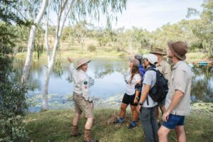 A guide with a group of people in nature by a lake in the australian bush
